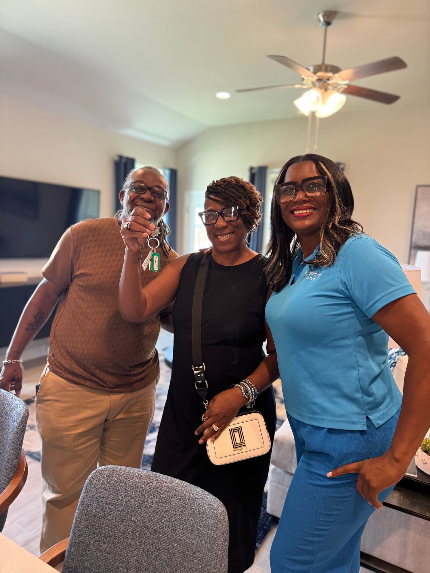 New homeowners holding up their first keys with their HomeStart coach